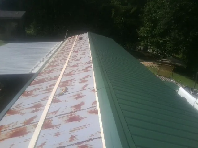 Old rusted panels beside newly installed green metal roofing — Wind Damage Roof Repair by Roofing Brothers in Mesquite