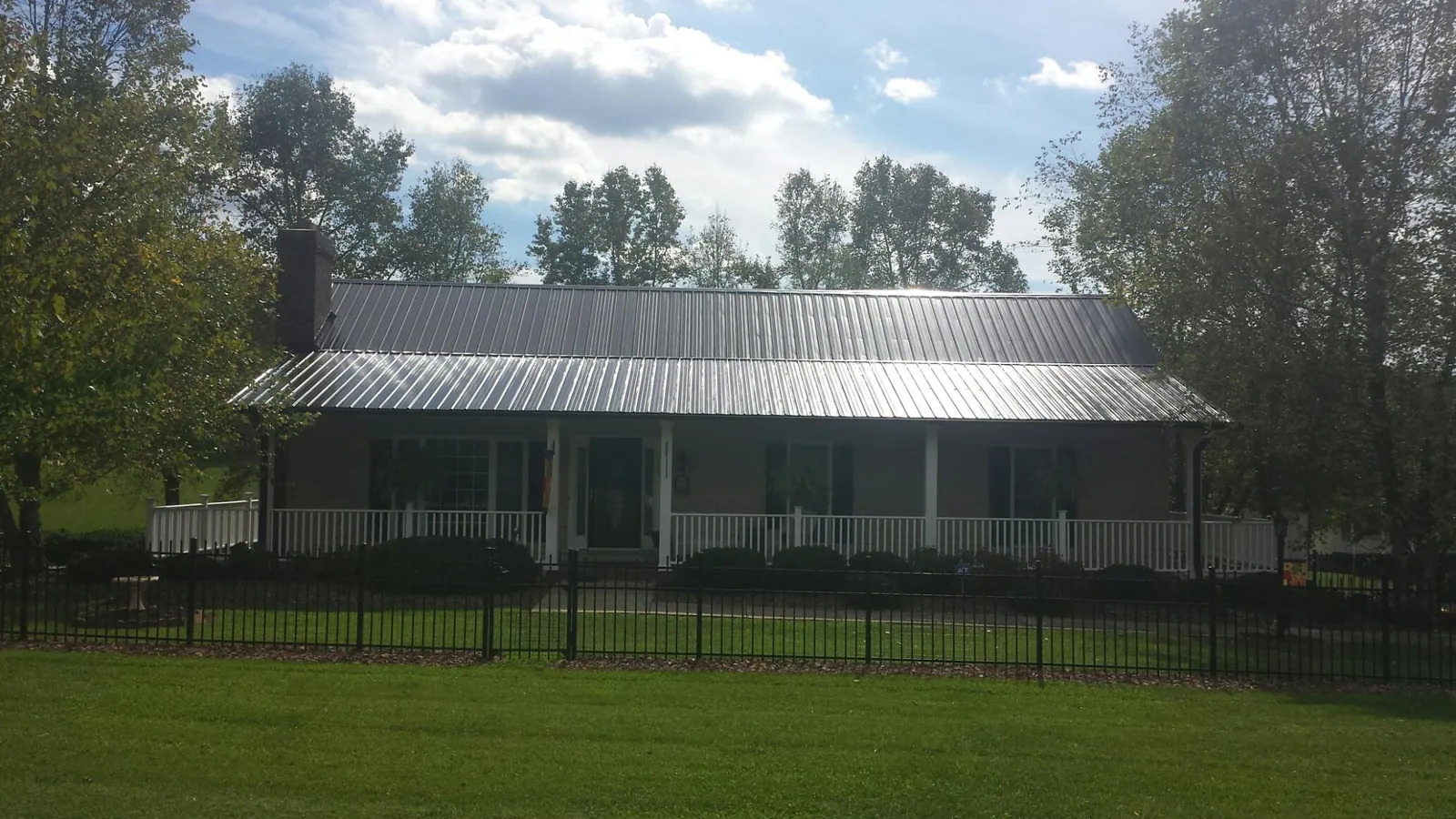 Gray metal roof on a brick ranch with a full width front porch — Gutter Guard Installation work by our crew in Mesquite