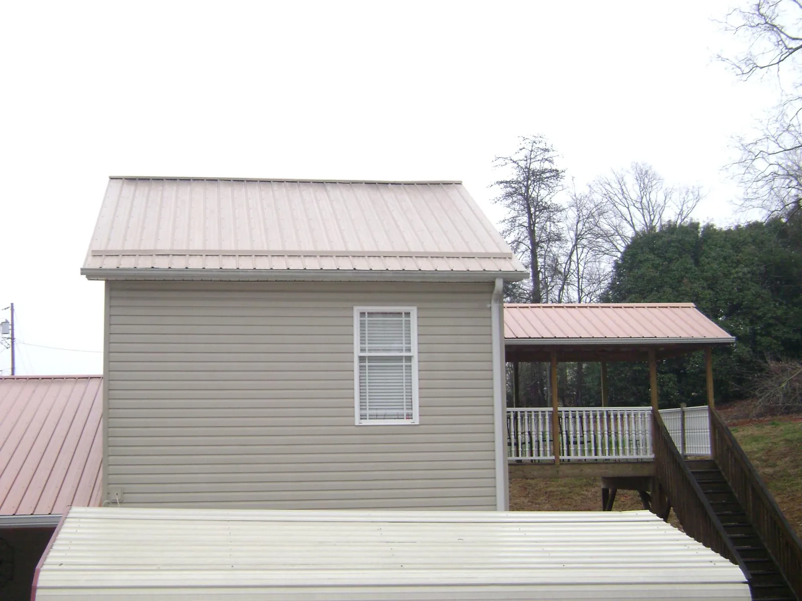 Tan metal roofs on a two story addition and attached porch, from a Roof Replacement job in Mesquite