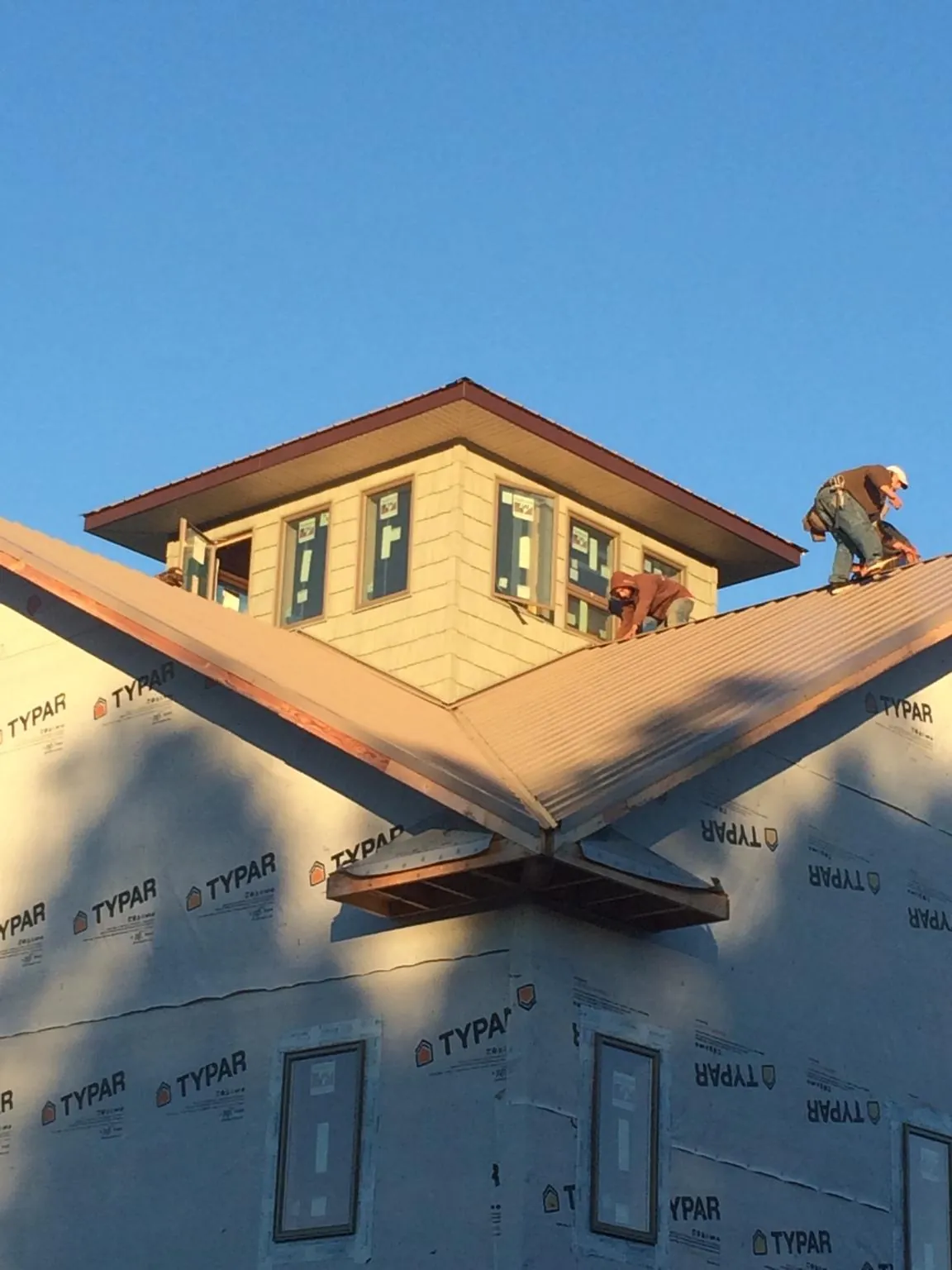 Roofers working around a rooftop cupola on a new metal roof at sunset — Roof Waterproofing in Mesquite by Roofing Brothers